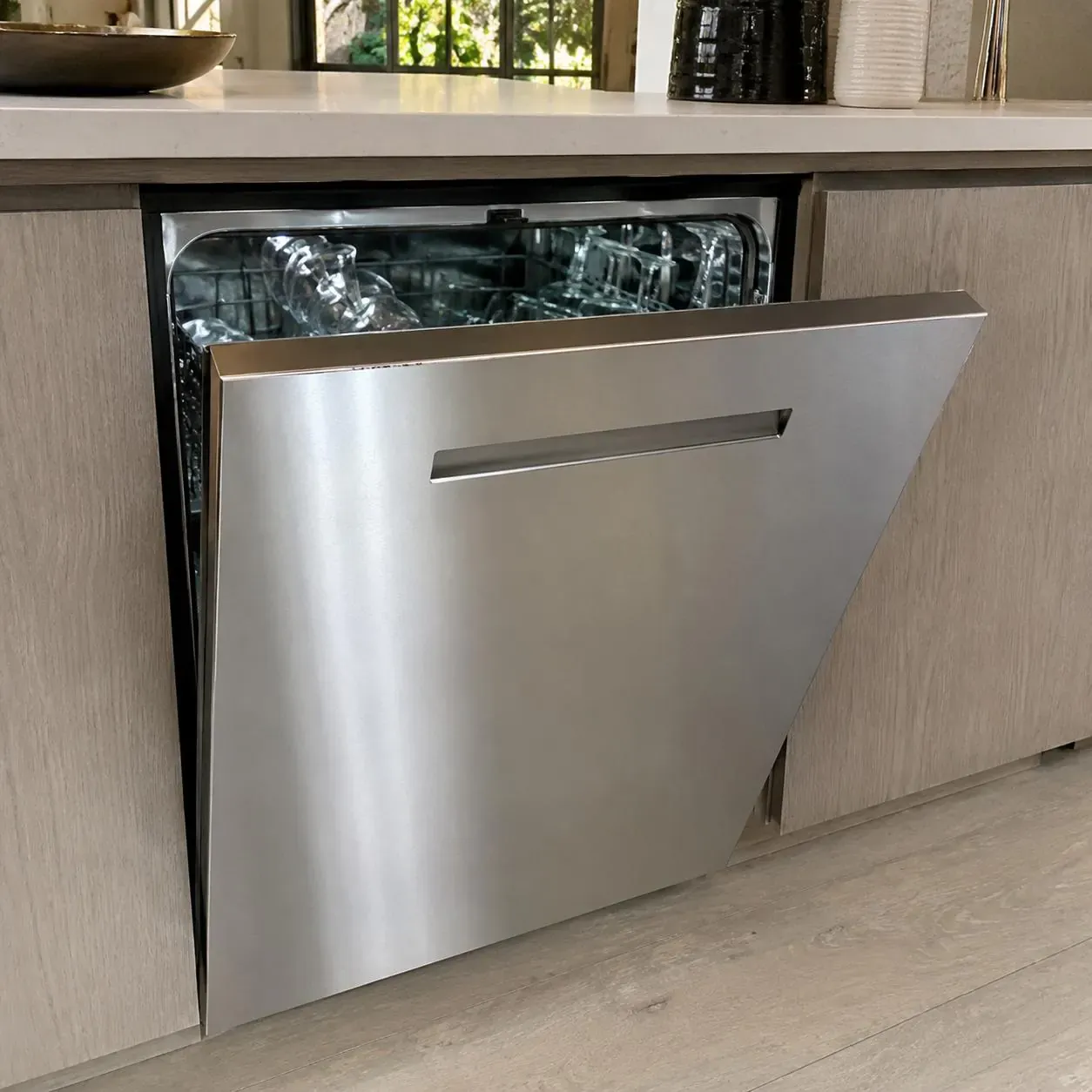 Stainless-fronted built-in dishwasher open with glassware on the racks
