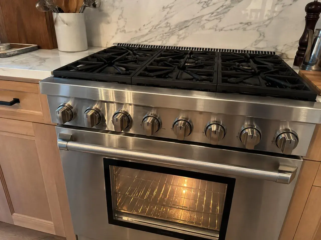 Professional stainless gas range with cast-iron grates and a glowing oven