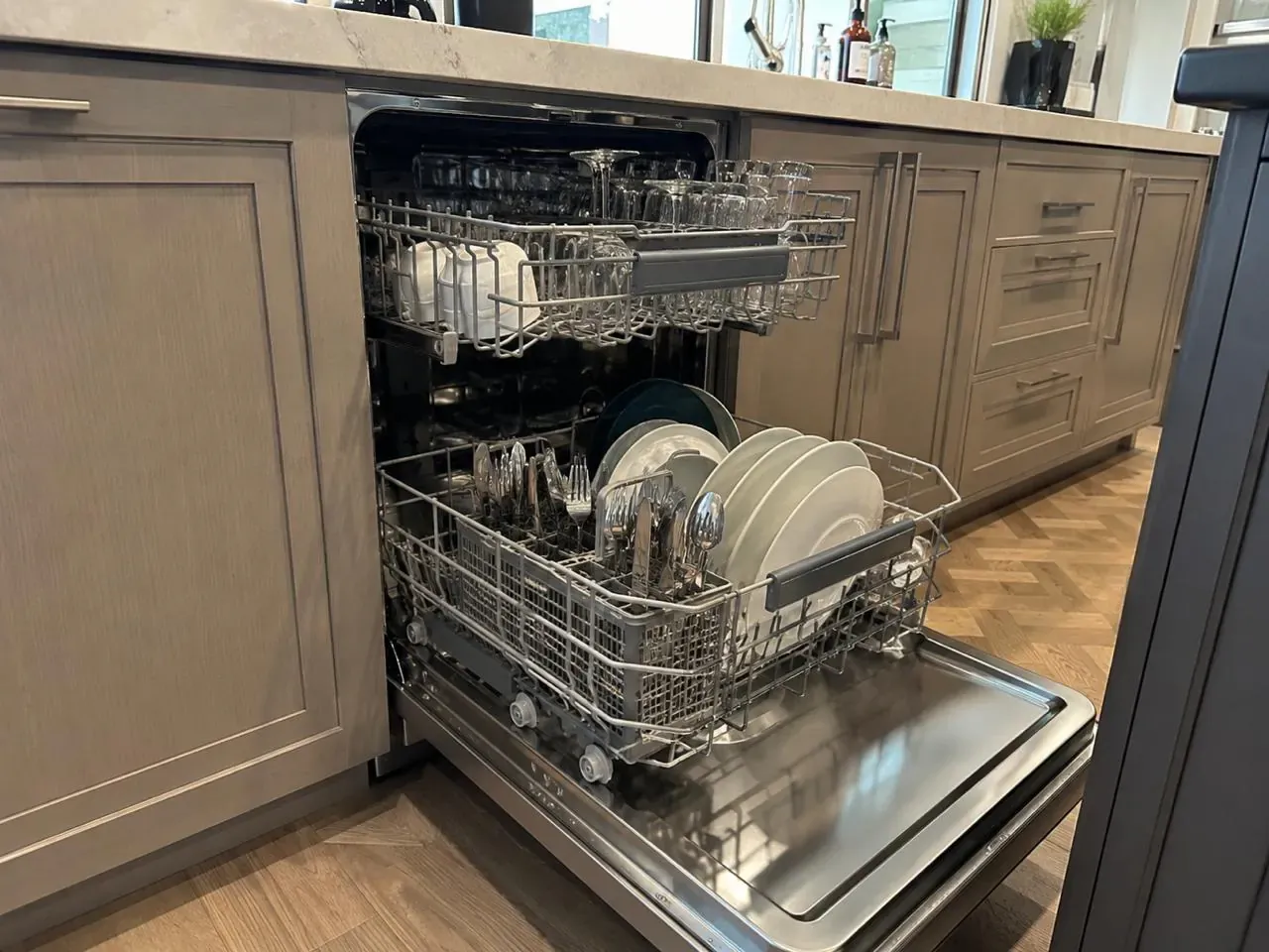 Built-in dishwasher open with clean glassware and plates on the racks