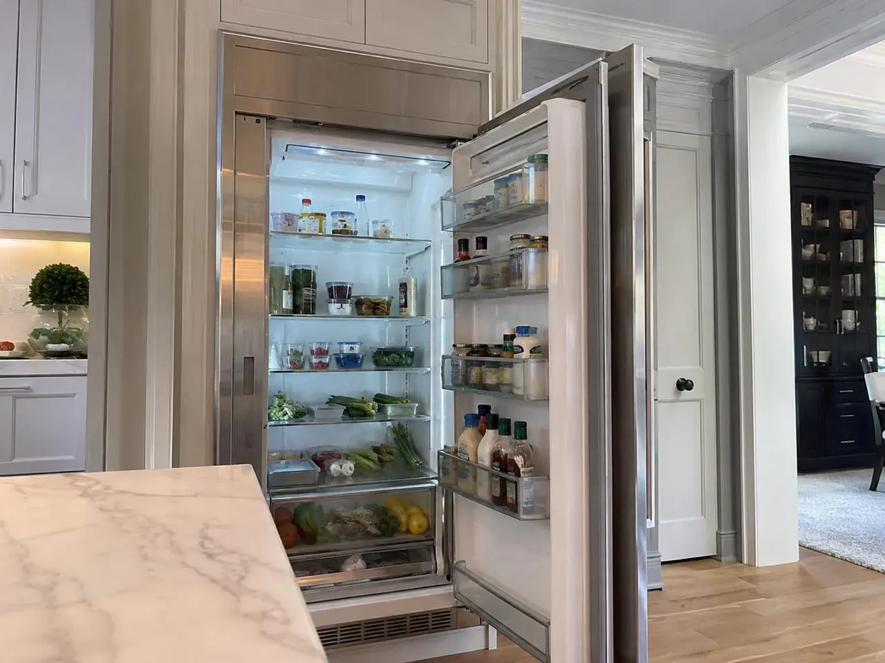 Open built-in column refrigerator stocked with fresh food in a luxury kitchen